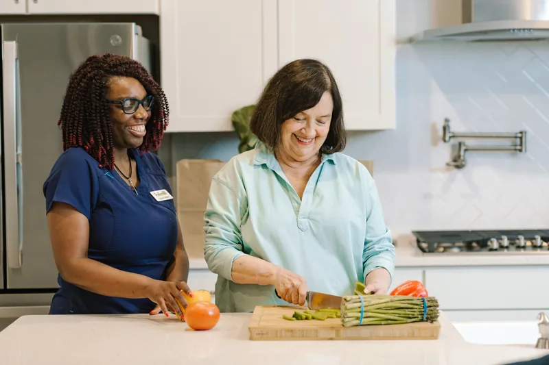 DayBreak caregiver supporting an older adult during meal preparation in the kitchen