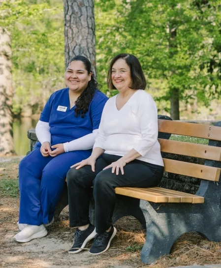 DayBreak caregiver sitting outdoors with an older adult client in a peaceful community setting